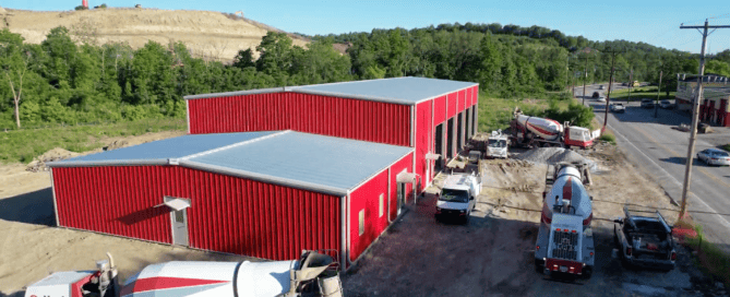Reflective standing-seam steel roof with solar panels and a green roof section on a modern commercial building
