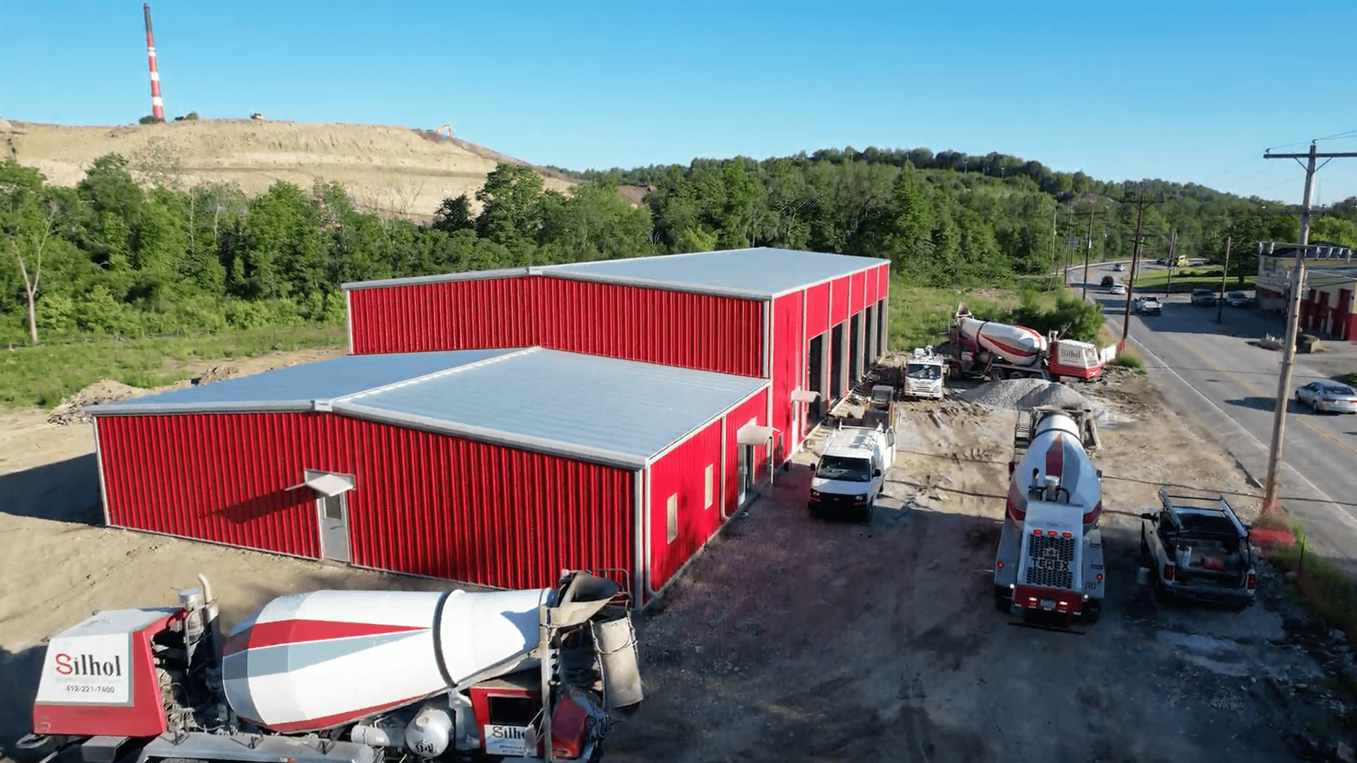 Reflective standing-seam steel roof with solar panels and a green roof section on a modern commercial building