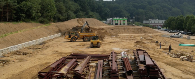 Midstream storage yard with steel equipment buildings, organized material areas, and energy infrastructure.