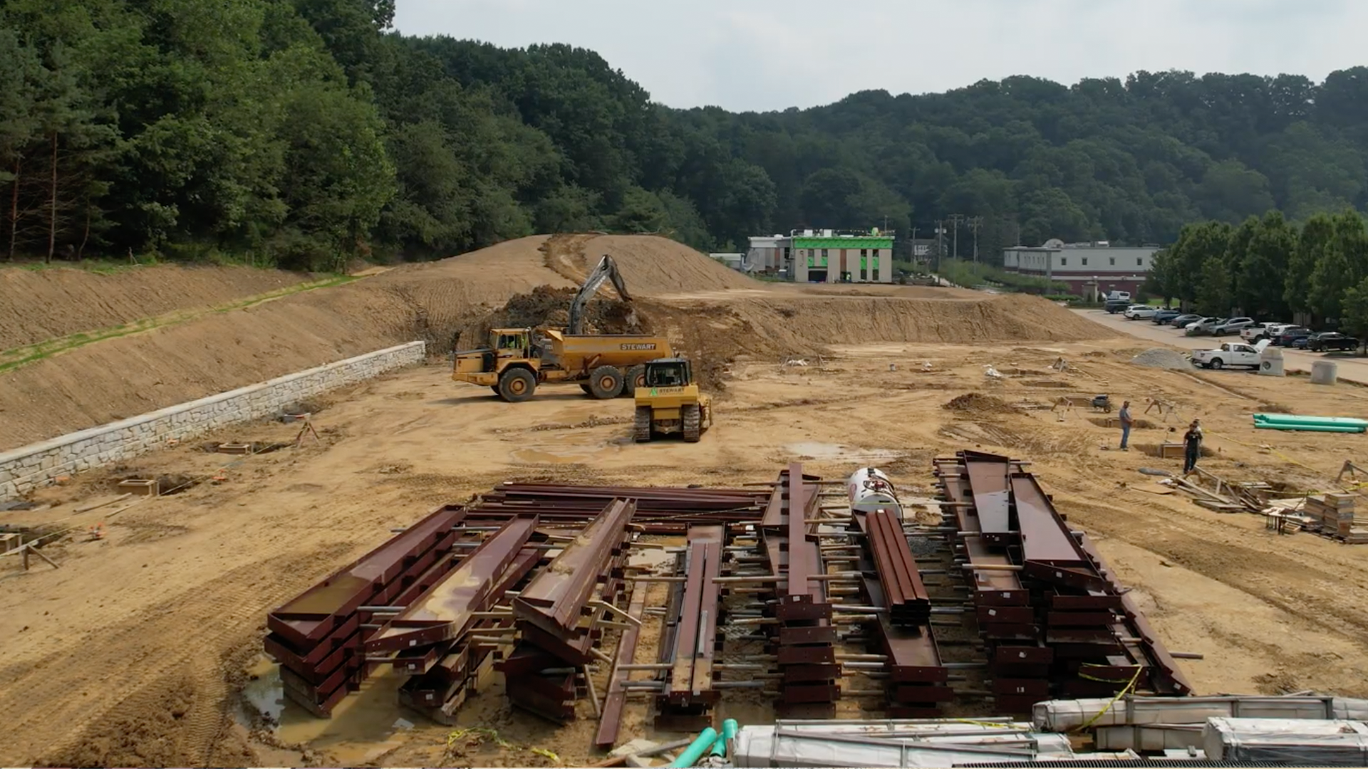 Midstream storage yard with steel equipment buildings, organized material areas, and energy infrastructure.